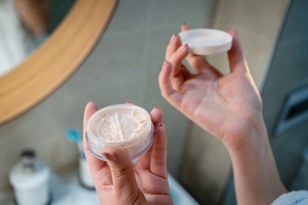 Close-up of person holding open face powder container, illustrating the proper handling for makeup application.