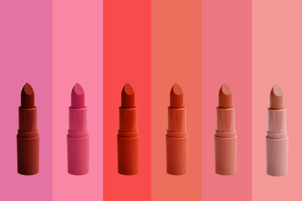 Six lipsticks in various shades of pink and red displayed in a row on a pink and red gradient background.