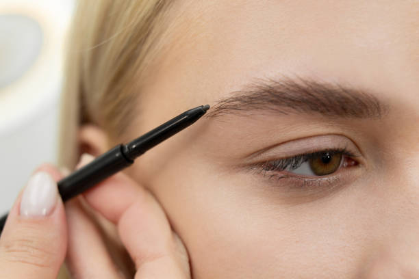 Close-up of a brow brush applying eyeshadow to fill in sparse areas and define the eyebrows.
