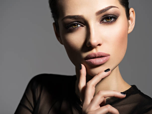 A model with flawless smokey eye makeup and nude lips poses elegantly, exemplifying eye makeup tips.